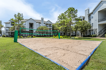 A sand volleyball court is surrounded by apartment buildings at Reserve by the Lake, Houston, Texas, 77084